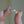 Gold ring with heart-shaped diamonds held between fingers against a neutral background
