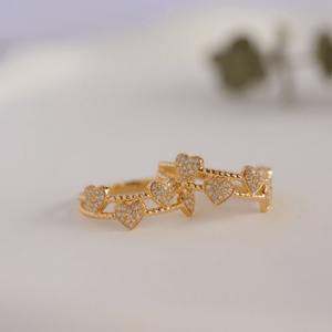 Gold ring with heart designs on a light background