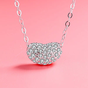 Two bean-shaped sterling silver necklaces with gold plating and cubic zirconia, one displayed in front of the other on a pink background.