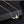 Gold necklace with a bird and heart pendant on a black background