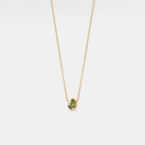 Gold necklace with a green gemstone pendant on a light gray background