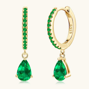 Gold hoop earrings with green gemstones on a white background