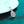 Teardrop-shaped diamond pendant on a chain against a teal background