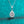 Teardrop-shaped diamond pendant on a chain against a teal glittery background