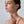 Woman wearing a small earring on a plain background
