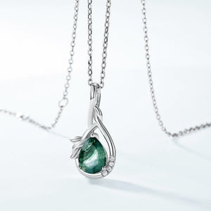Silver pendant with a green gemstone on a white background