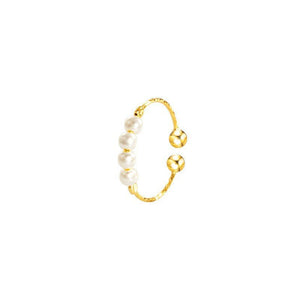 A ring with white pearls and gold plating, displayed on a black fabric surface.
