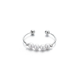 A ring with white pearls and gold plating, displayed on a black fabric surface.