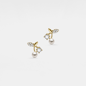 Pair of gold earrings with pearls and crystals on a light gray background