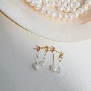 Pearl earrings with gold hooks on a light background