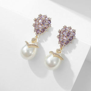 Pair of earrings with purple gemstones and pearl-like elements on a light background