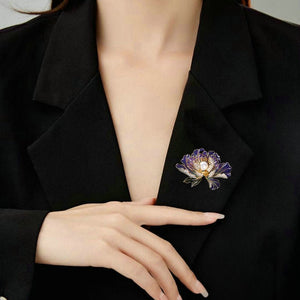 Person wearing a black blazer with a decorative brooch on a neutral background