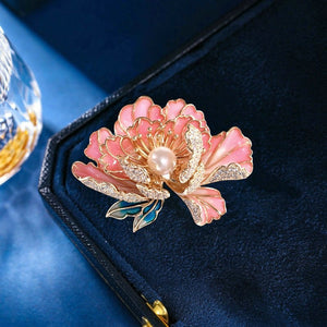 Pink floral brooch with pearl center on a dark blue velvet background
