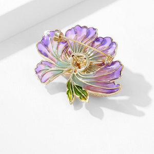 Colorful flower-shaped brooch with gold accents on a white background
