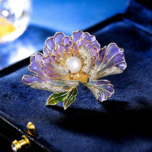 Decorative brooch with purple floral design and pearl center on a blue background