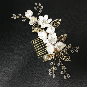 Floral hair comb with white flowers and gold leaves on a black textured background