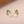 Pearl earrings with green leaf-like designs on a beige background