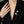 Person wearing a black blazer with a decorative brooch on a neutral background