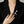 Person wearing a black blazer with a decorative brooch on a neutral background