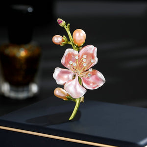 Decorative brooch with pink flowers and pearls on a dark surface