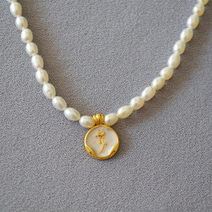 A collection of three pearl necklace chains with gold-plated rose flower pendants, displayed on a grey background.