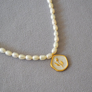 A collection of three pearl necklace chains with gold-plated rose flower pendants, displayed on a grey background.