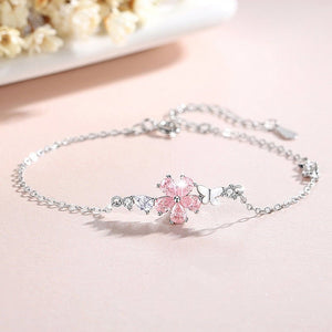 Silver bracelet with a pink flower charm on a light pink background