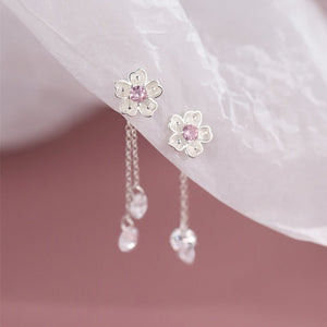 Flower-shaped earrings with pink centers and dangling crystals on a soft background