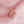 Rose gold ring with a pink flower-shaped gemstone on a pink fabric background