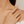Close-up of a hand wearing a delicate silver ring with pink gemstones on a neutral background
