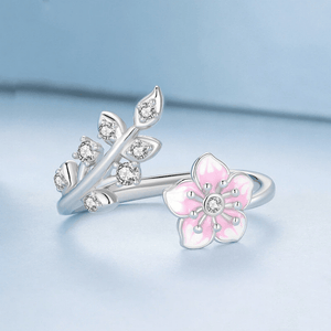 Silver ring with pink flower design on a light blue background