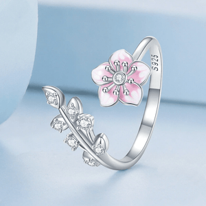 Silver ring with pink flower design on a light blue background