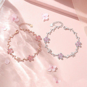Two floral anklets on a soft pink fabric background with cherry blossom petals.