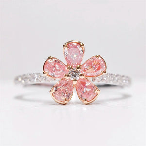 Ring with pink gemstone flower design on a light gray background