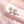 A set of cherry blossom stud earrings in various colors including pink and white, displayed on a soft, floral background.