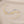 Two gold and silver bracelets with floral designs on a beige fabric background