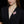 Woman wearing a black blazer with a pink floral brooch against a black background