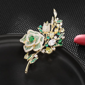 Gold brooch with green gemstones on a black background