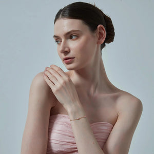 Woman wearing a strapless pink dress against a plain background