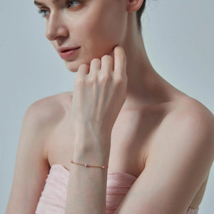 Woman wearing a delicate bracelet on a plain background