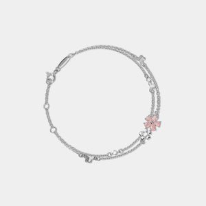 Silver bracelet with a pink flower charm on a light gray background
