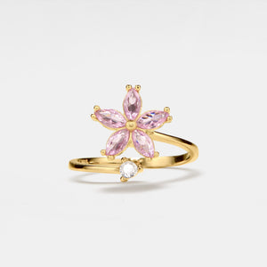 Gold ring with pink gemstones on a light gray background