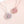 Two pink clover-shaped pendants on necklaces against a light pink background