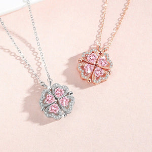 Two pink clover-shaped pendants on necklaces against a light pink background