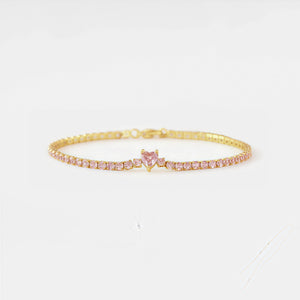 Gold bracelet with pink heart-shaped gemstone on a white background