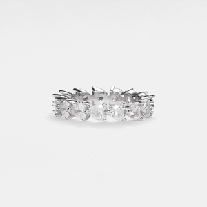 A silver eternity ring with pink heart-shaped gemstones arranged in a circle.