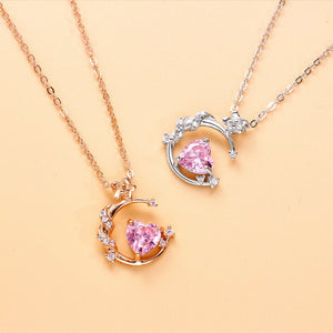 Two heart-shaped pink gemstone pendants on gold and silver chains against a beige background.