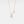 Gold necklace with a pink heart-shaped pendant on a light gray background