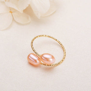 Gold ring with two pink pearls on a light background
