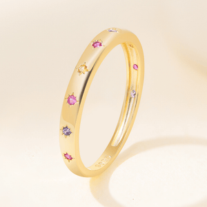 Gold ring with colorful gemstones on a beige background